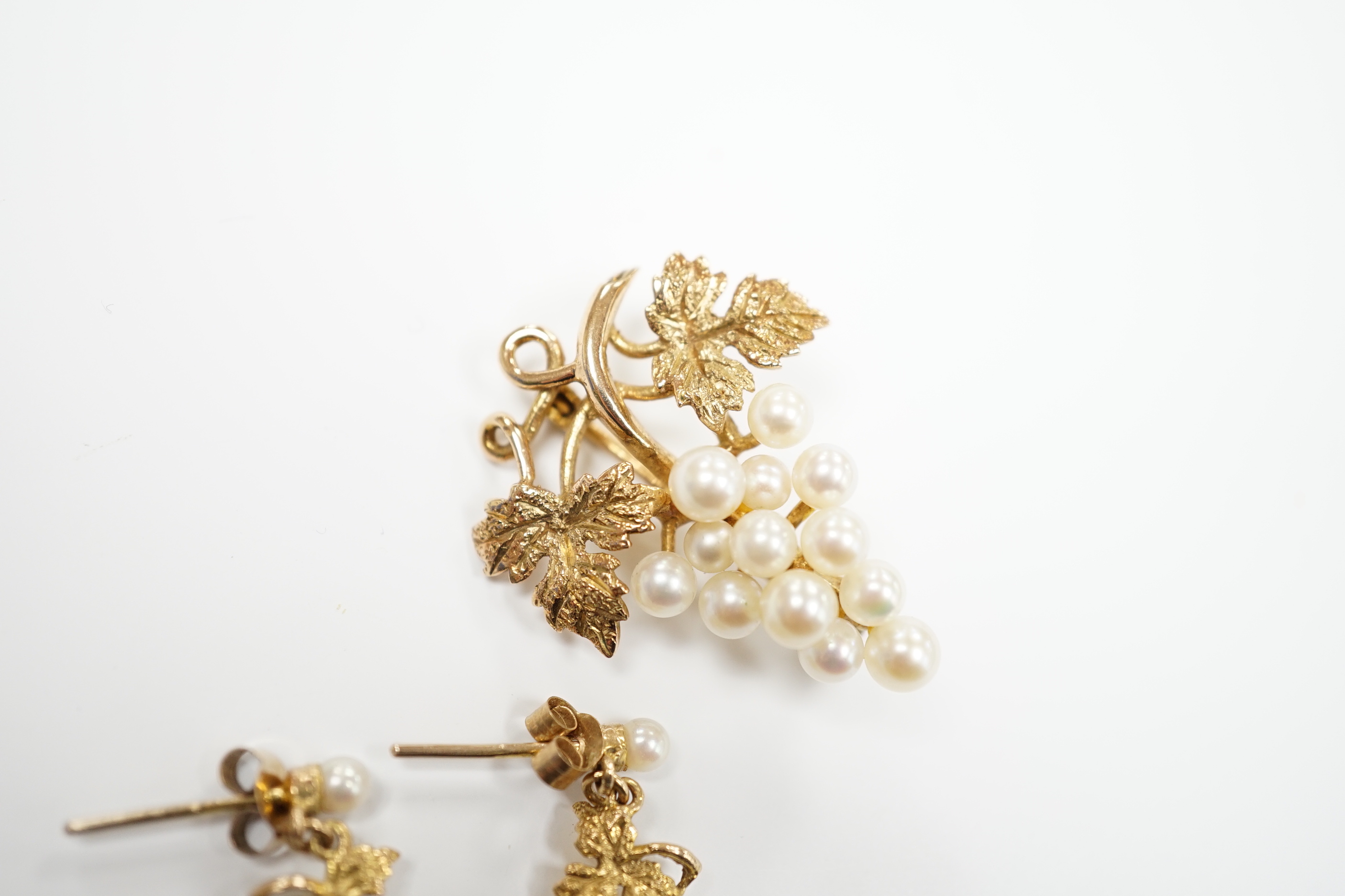 A modern 9ct gold and cultured pearl cluster set suite of jewellery, modelled as a bunch of grapes, comprising a brooch and pair of earrings, gross weight 7.3 grams.